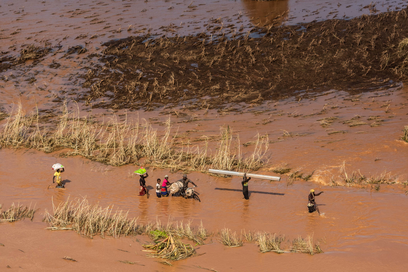 People wade through flood waters in the rural neighborhood of Buzi in Mozambique on March 24, 2019.